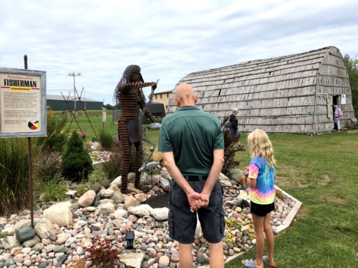 Man and child look an outdoor sculpture exhibit at the Museum of Ojibwa Culture.